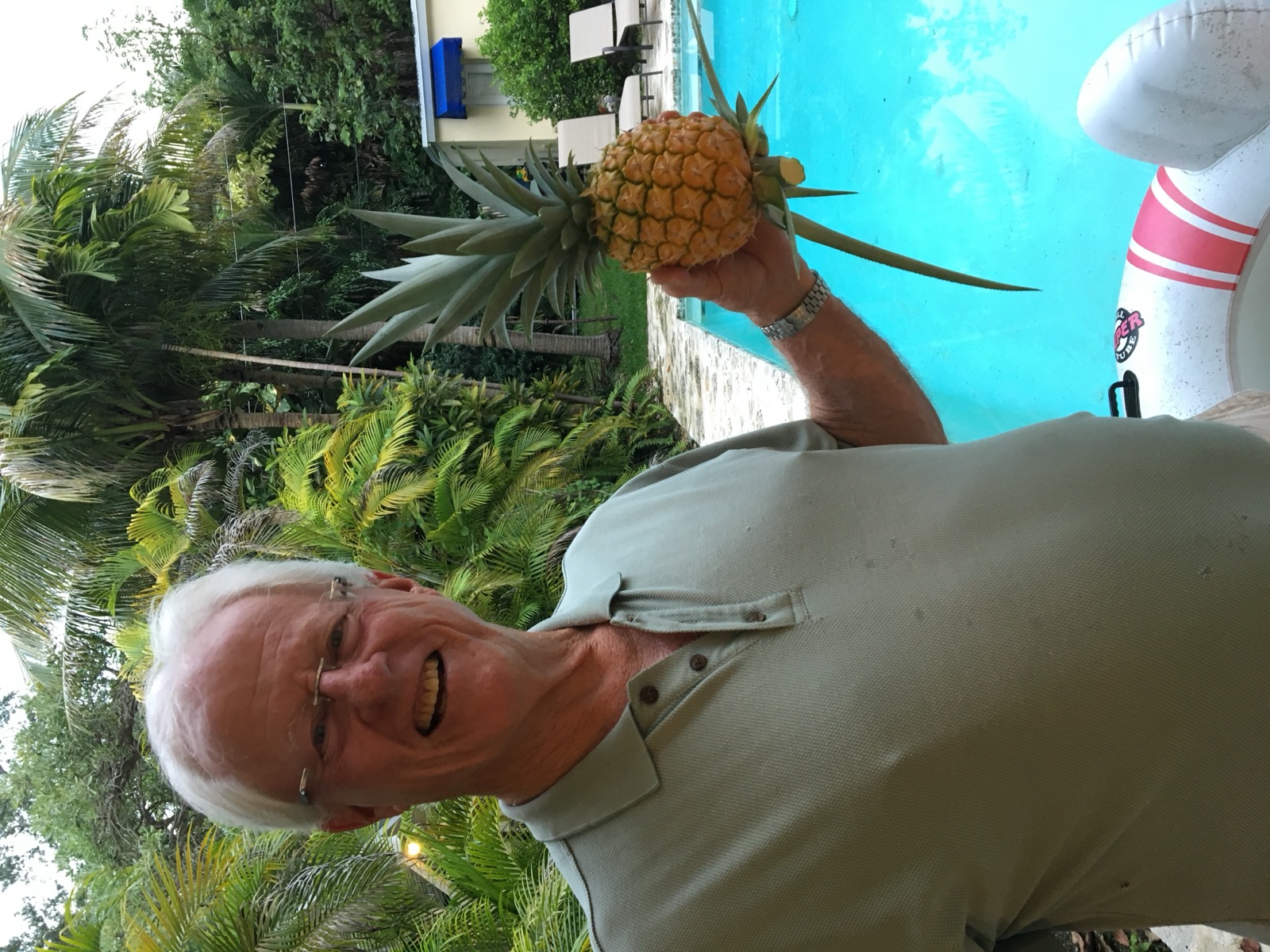 John holding a pineapple in the garden by the pool